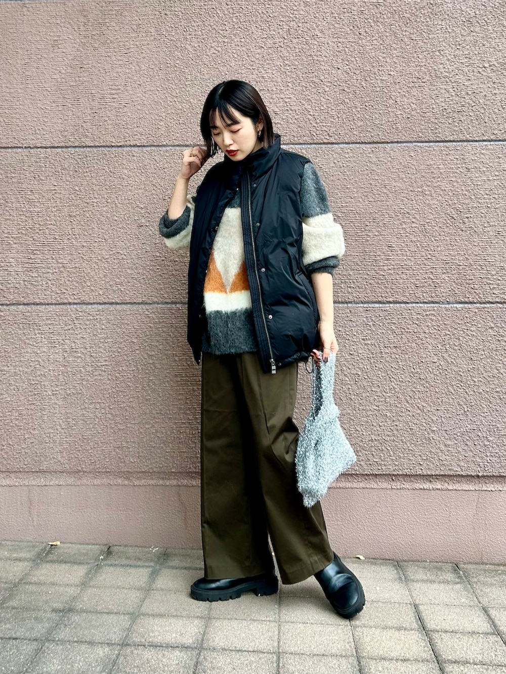 ブラック系のダウンベスト、グレー系のニット/セーター、グリーン系のその他パンツを着用したレディースの冬コーディネートの2枚目の写真