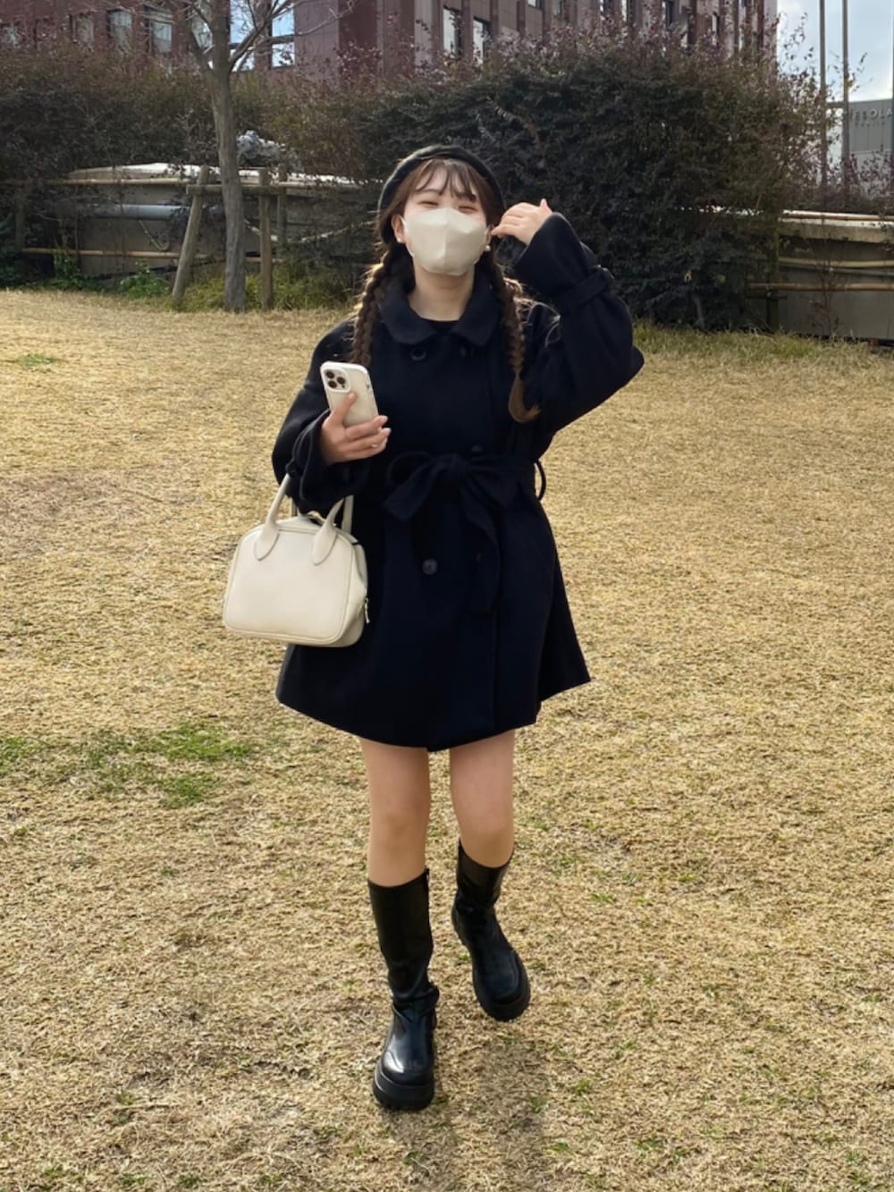 ブラック系のステンカラーコート、ブラック系のブーツを着用したレディースの冬コーディネートの2枚目の写真