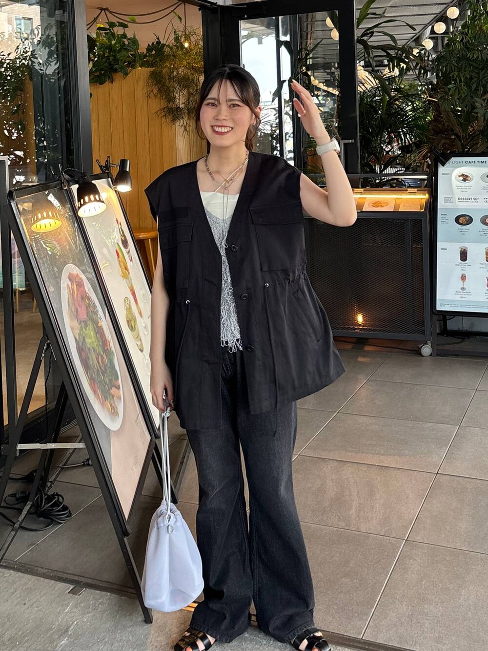 グレー系のショルダーバッグ、ブラック系のサンダル、ホワイト系のベストを着用したレディースの夏コーディネートの3枚目の写真