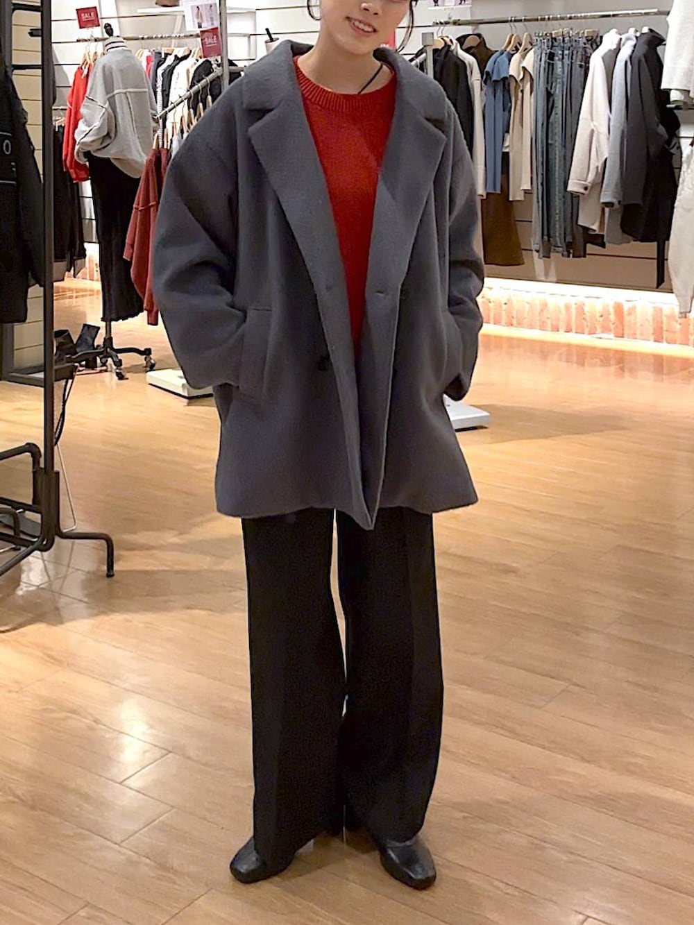 レッド系のニット/セーター、ブラック系のブーツ、ブラック系のその他パンツを着用したレディースの冬コーディネートの2枚目の写真