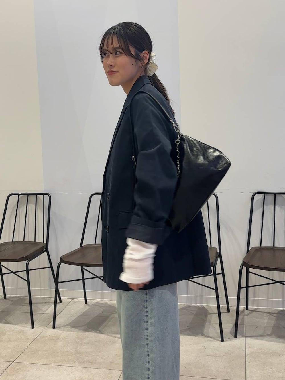 ブルー系のデニムパンツ、ブラック系のショルダーバッグ、ブラック系のローファーを着用したレディースの春コーディネートの4枚目の写真