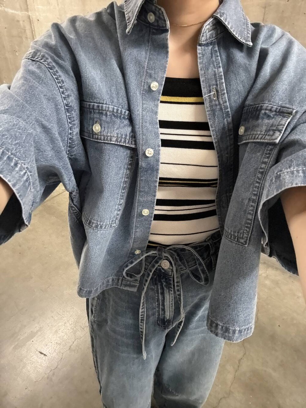 シルバー系のサンダル、ブルー系のデニムパンツ、ブラック系のショルダーバッグを着用したレディースの夏コーディネートの5枚目の写真