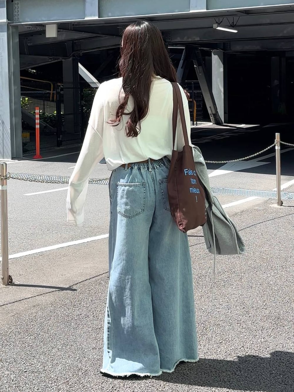 ホワイト系のTシャツ/カットソー、ブラウン系のトートバッグ、ブルー系のデニムパンツを着用したレディースの春コーディネートの4枚目の写真