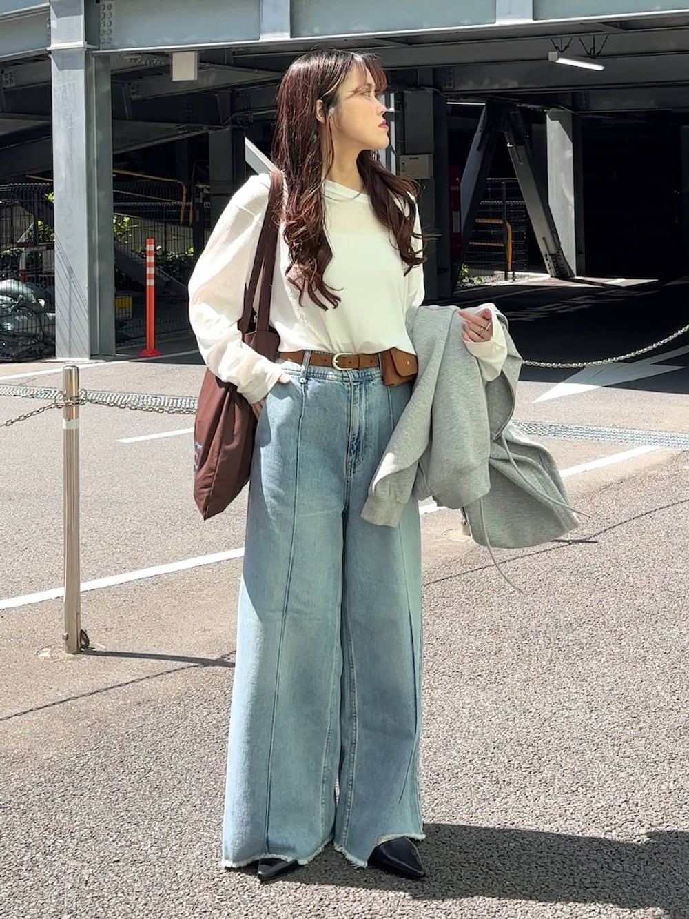 ホワイト系のTシャツ/カットソー、ブラウン系のトートバッグ、ブルー系のデニムパンツを着用したレディースの春コーディネートの5枚目の写真