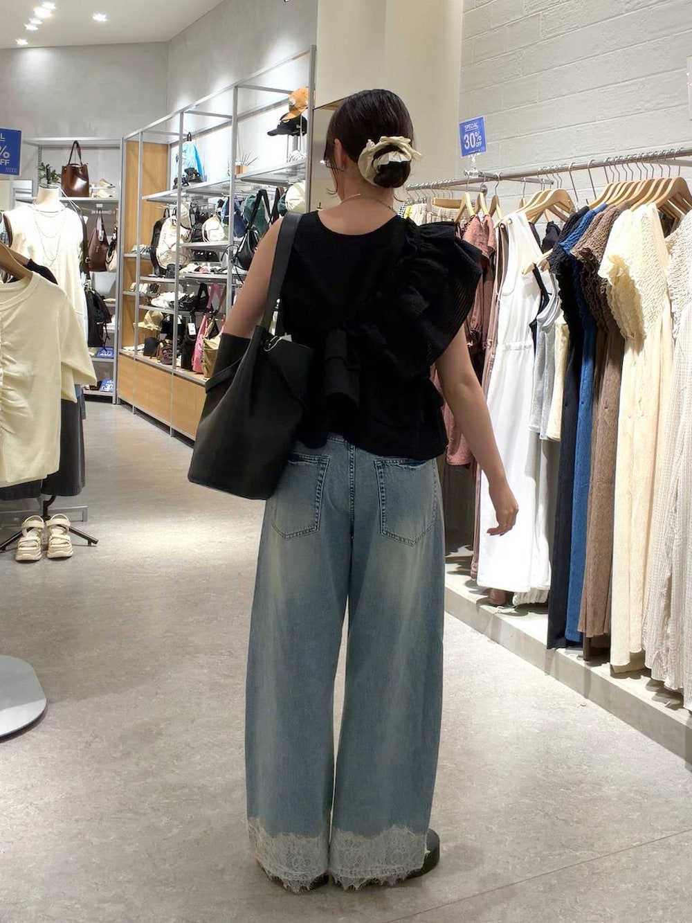 ブルー系のデニムパンツ、ブラック系のトートバッグ、シルバー系のサンダルを着用したレディースの夏コーディネートの3枚目の写真