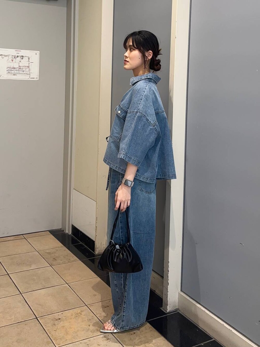 シルバー系のサンダル、ブルー系のデニムパンツ、ブラック系のショルダーバッグを着用したレディースの夏コーディネートの2枚目の写真