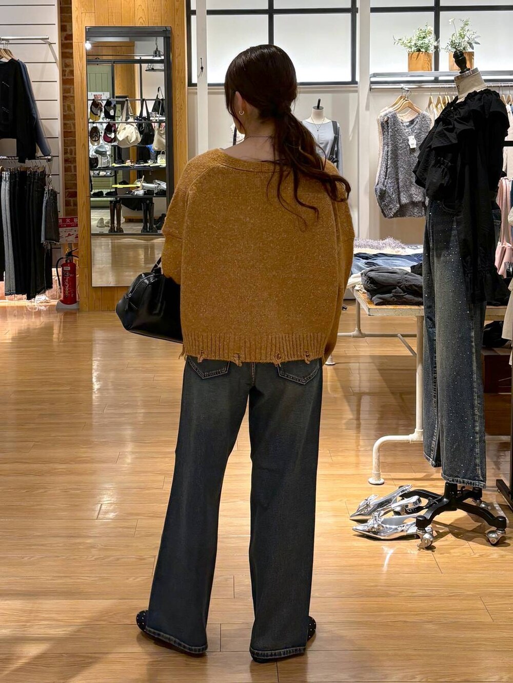 ブルー系のデニムパンツ、ブラック系のバレエシューズ、ブラック系のボストンバッグを着用したレディースの秋コーディネートの4枚目の写真