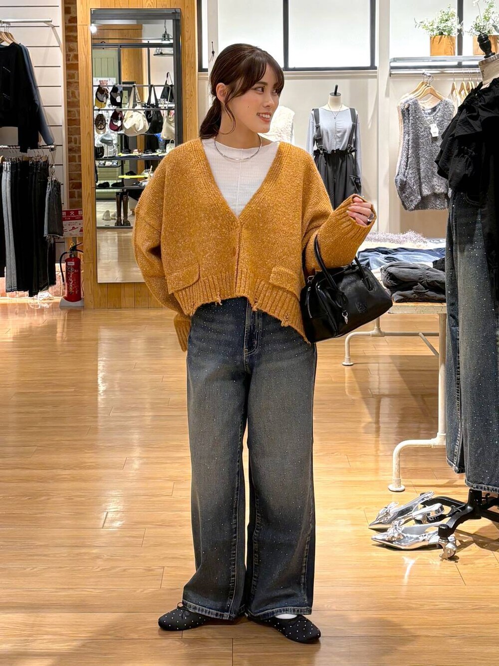 ブルー系のデニムパンツ、ブラック系のバレエシューズ、ブラック系のボストンバッグを着用したレディースの秋コーディネートの2枚目の写真