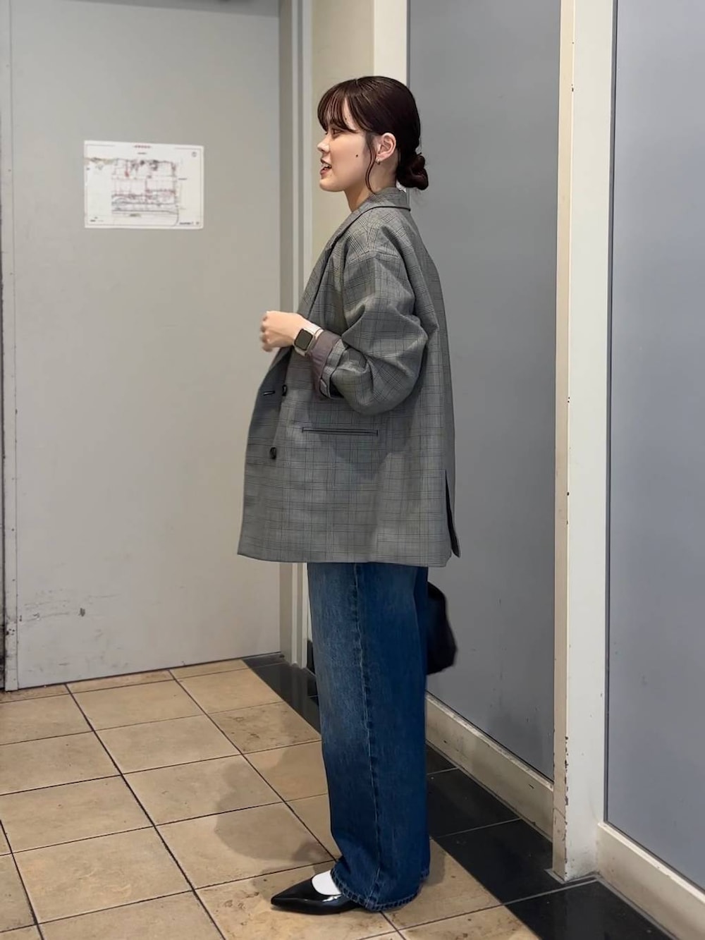 グレー系のテーラードジャケット、ブラック系のショルダーバッグ、ブルー系のデニムパンツを着用したレディースの秋コーディネートの3枚目の写真