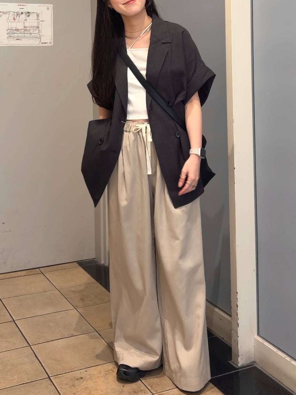 ベージュ系のデニムパンツ、グレー系のテーラードジャケット、ブラック系のショルダーバッグを着用したレディースの夏コーディネートの4枚目の写真