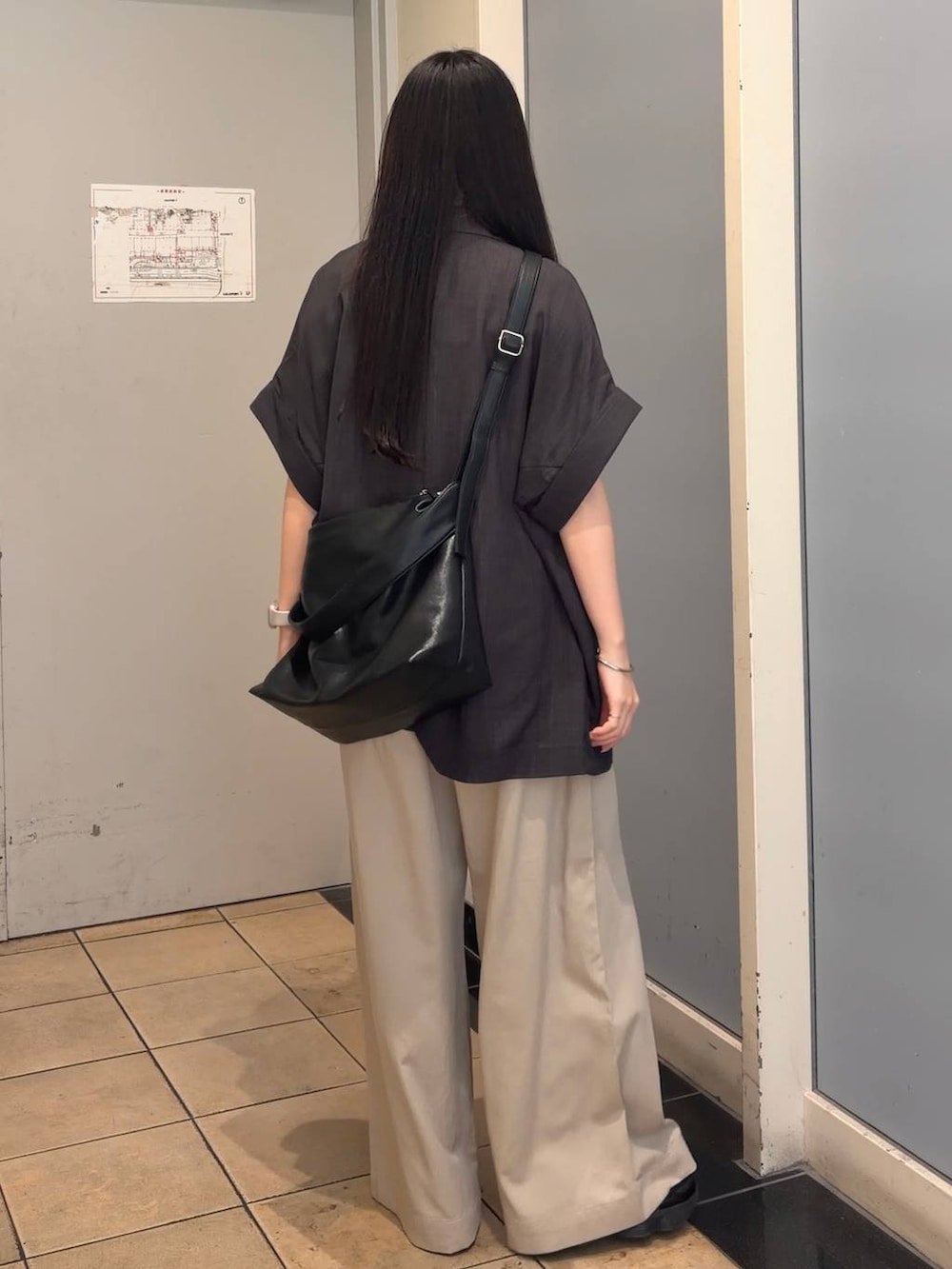 ベージュ系のデニムパンツ、グレー系のテーラードジャケット、ブラック系のショルダーバッグを着用したレディースの夏コーディネートの3枚目の写真