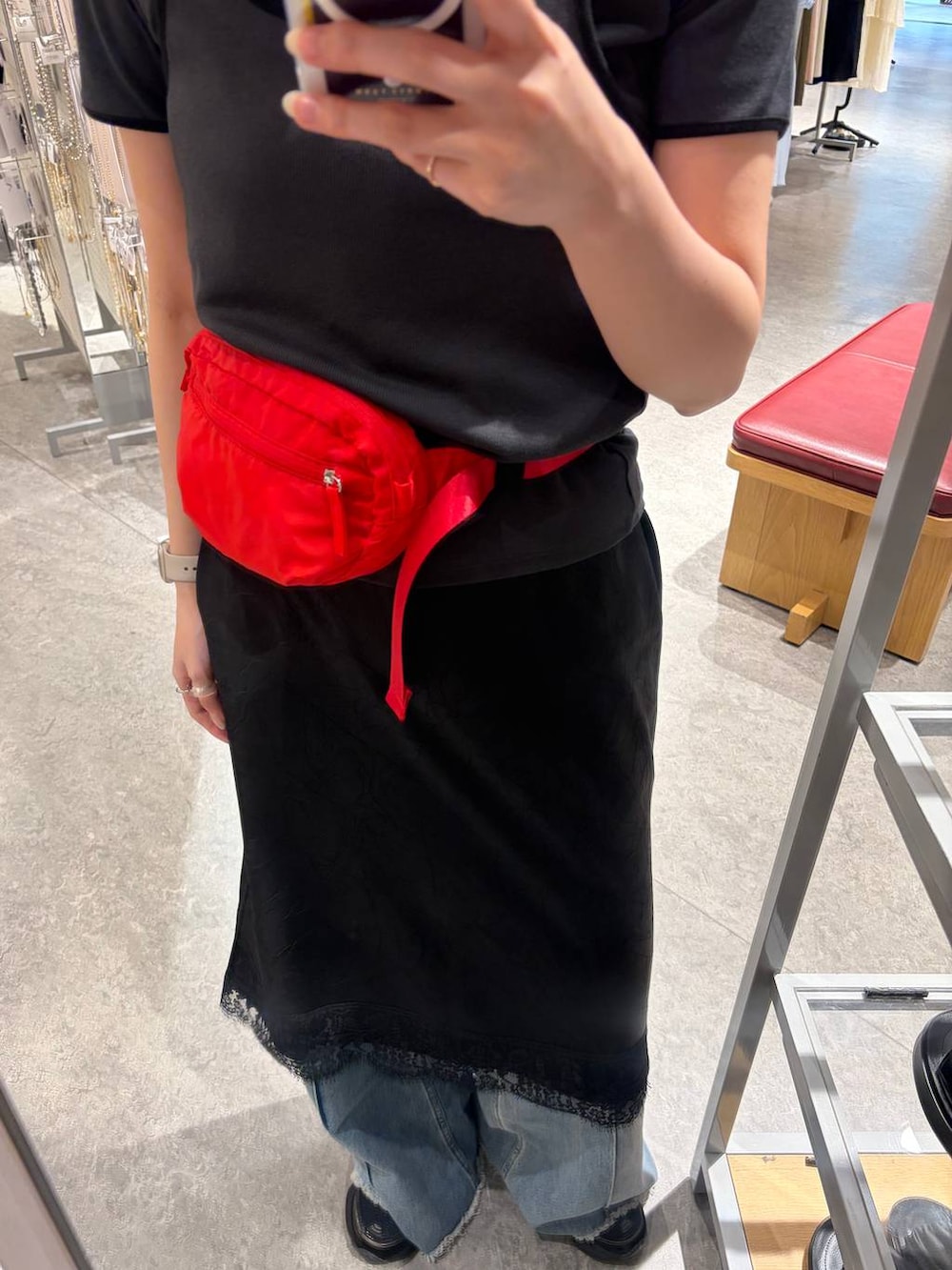ブルー系のデニムパンツ、レッド系のボディバッグ/ウエストポーチ、ブラック系のスカートを着用したレディースの春コーディネートの3枚目の写真