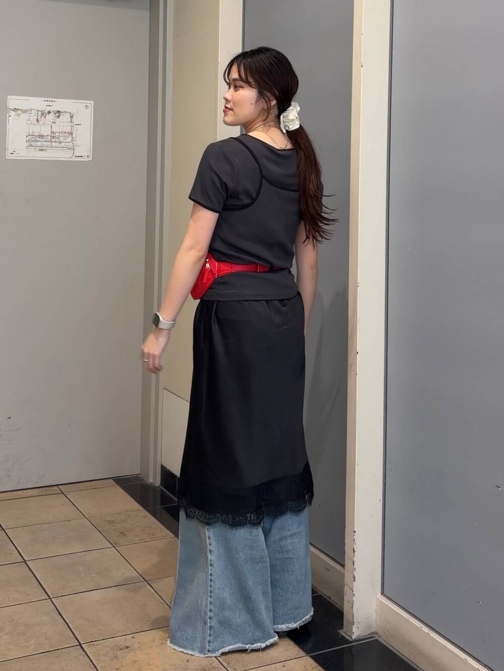 ブルー系のデニムパンツ、レッド系のボディバッグ/ウエストポーチ、ブラック系のスカートを着用したレディースの春コーディネートの3枚目の写真