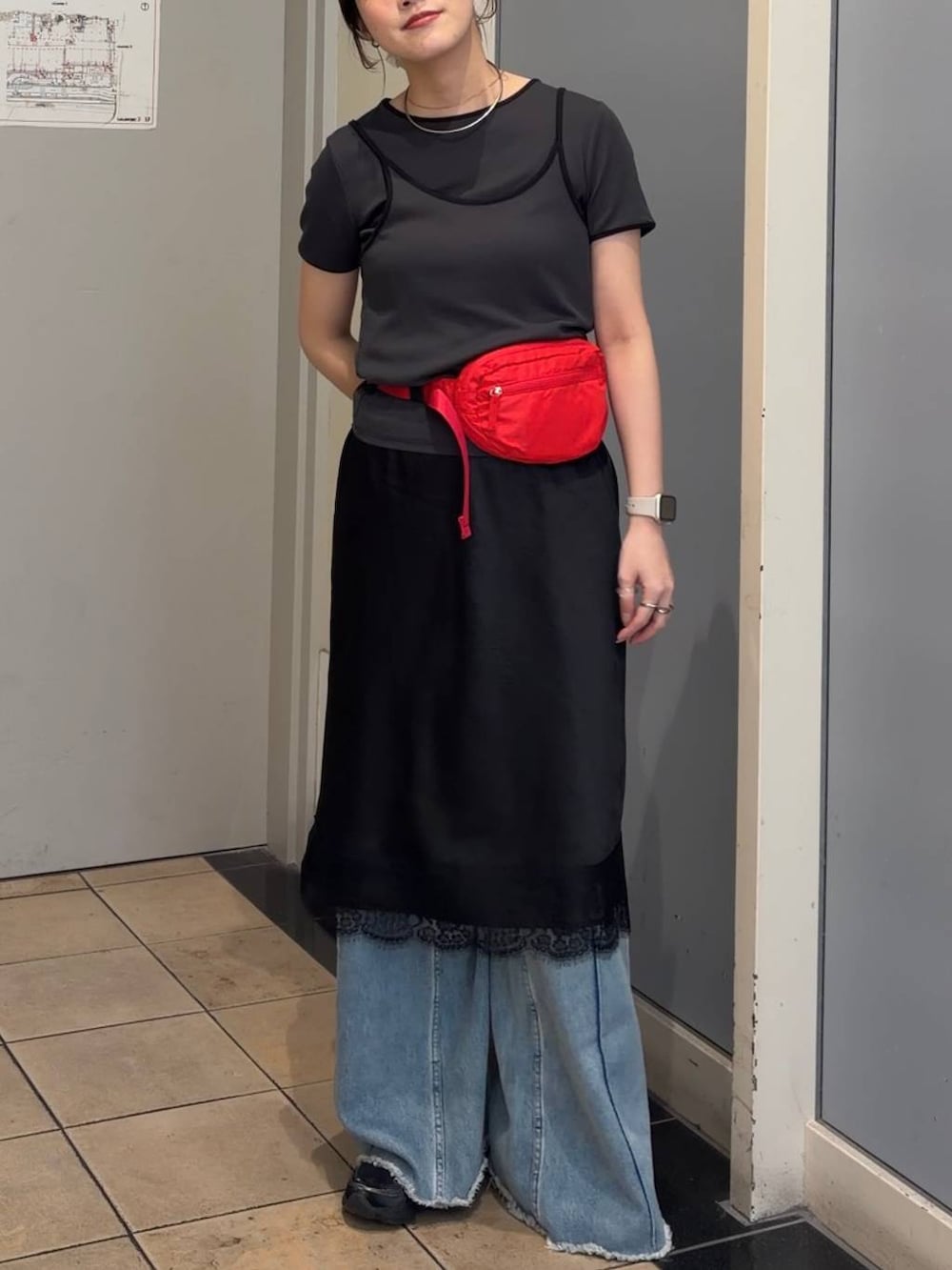 ブルー系のデニムパンツ、レッド系のボディバッグ/ウエストポーチ、ブラック系のスカートを着用したレディースの春コーディネートの4枚目の写真