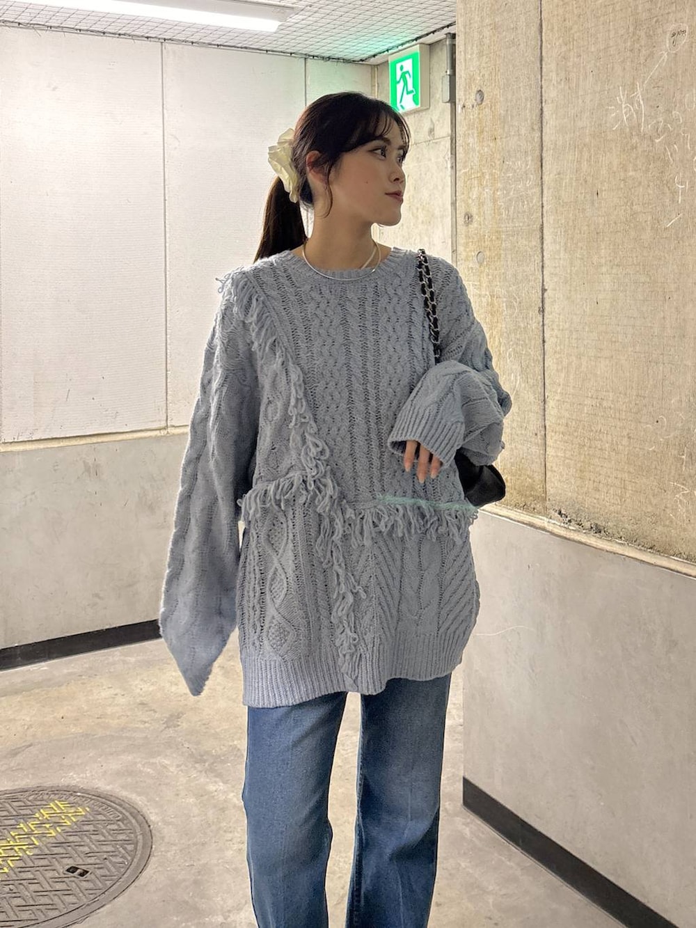 ブルー系のニット/セーター、ブルー系のデニムパンツ、ブラック系のショルダーバッグを着用したレディースの秋コーディネートの2枚目の写真