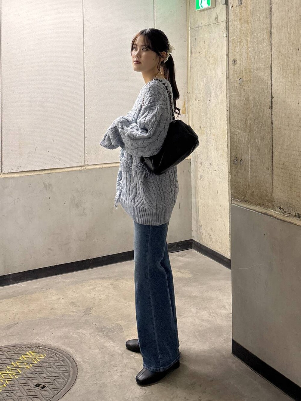 ブルー系のニット/セーター、ブルー系のデニムパンツ、ブラック系のショルダーバッグを着用したレディースの秋コーディネートの4枚目の写真