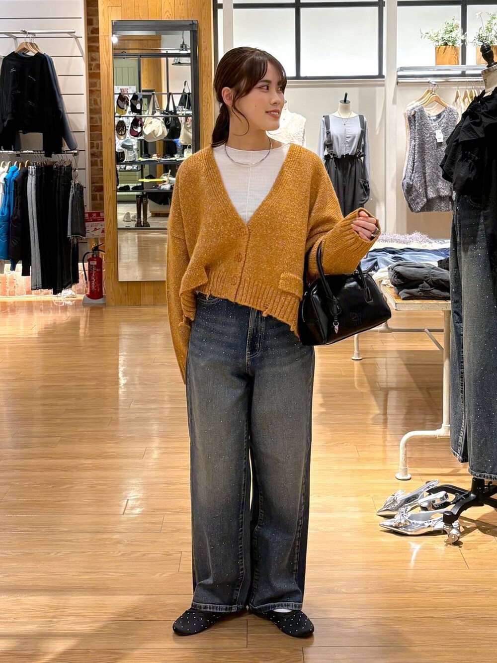 ブルー系のデニムパンツ、ブラック系のバレエシューズ、ブラック系のボストンバッグを着用したレディースの秋コーディネートの5枚目の写真