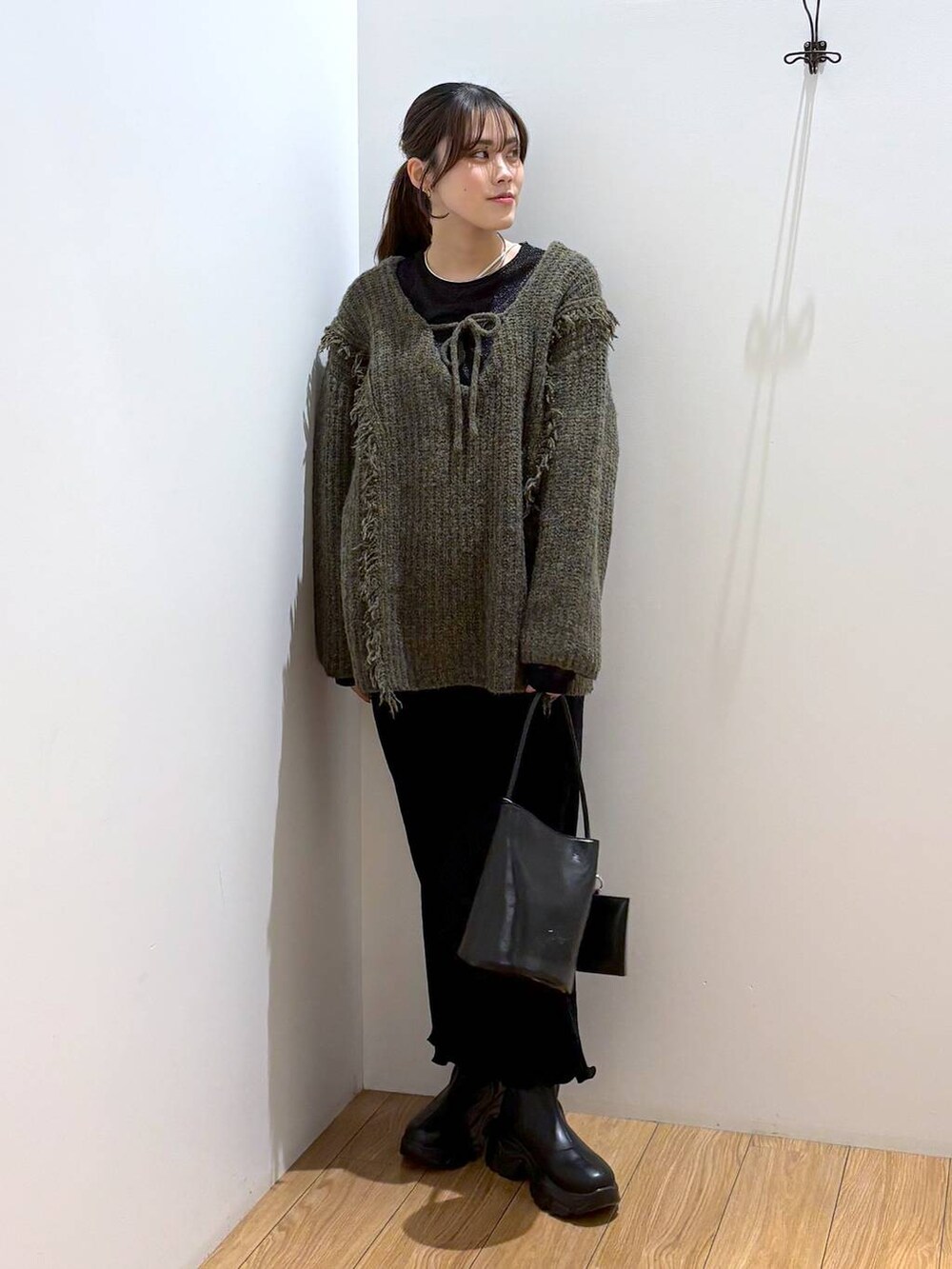 グリーン系のニット/セーター、ブラック系のTシャツ/カットソー、ブラック系のブーツを着用したレディースの冬コーディネートの2枚目の写真