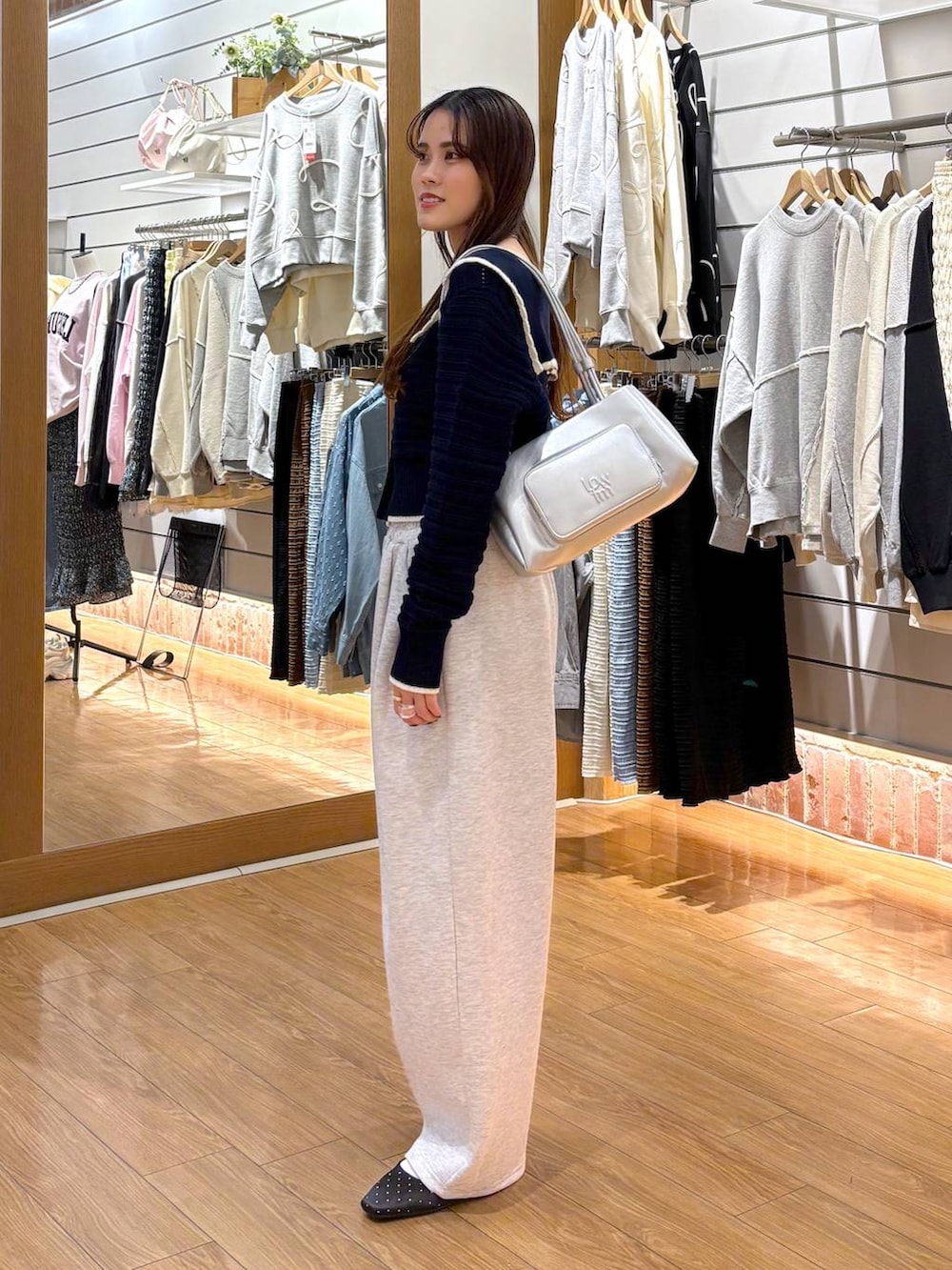 シルバー系のショルダーバッグ、ブルー系のニット/セーター、グレー系のスウェットパンツを着用したレディースの冬コーディネートの3枚目の写真