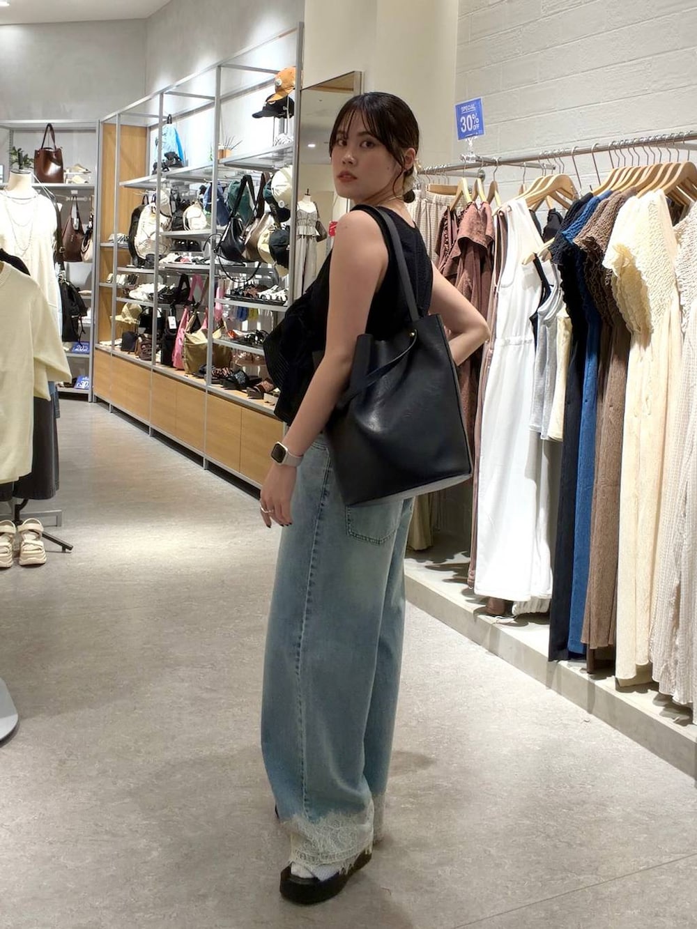 ブルー系のデニムパンツ、ブラック系のトートバッグ、シルバー系のサンダルを着用したレディースの夏コーディネートの2枚目の写真
