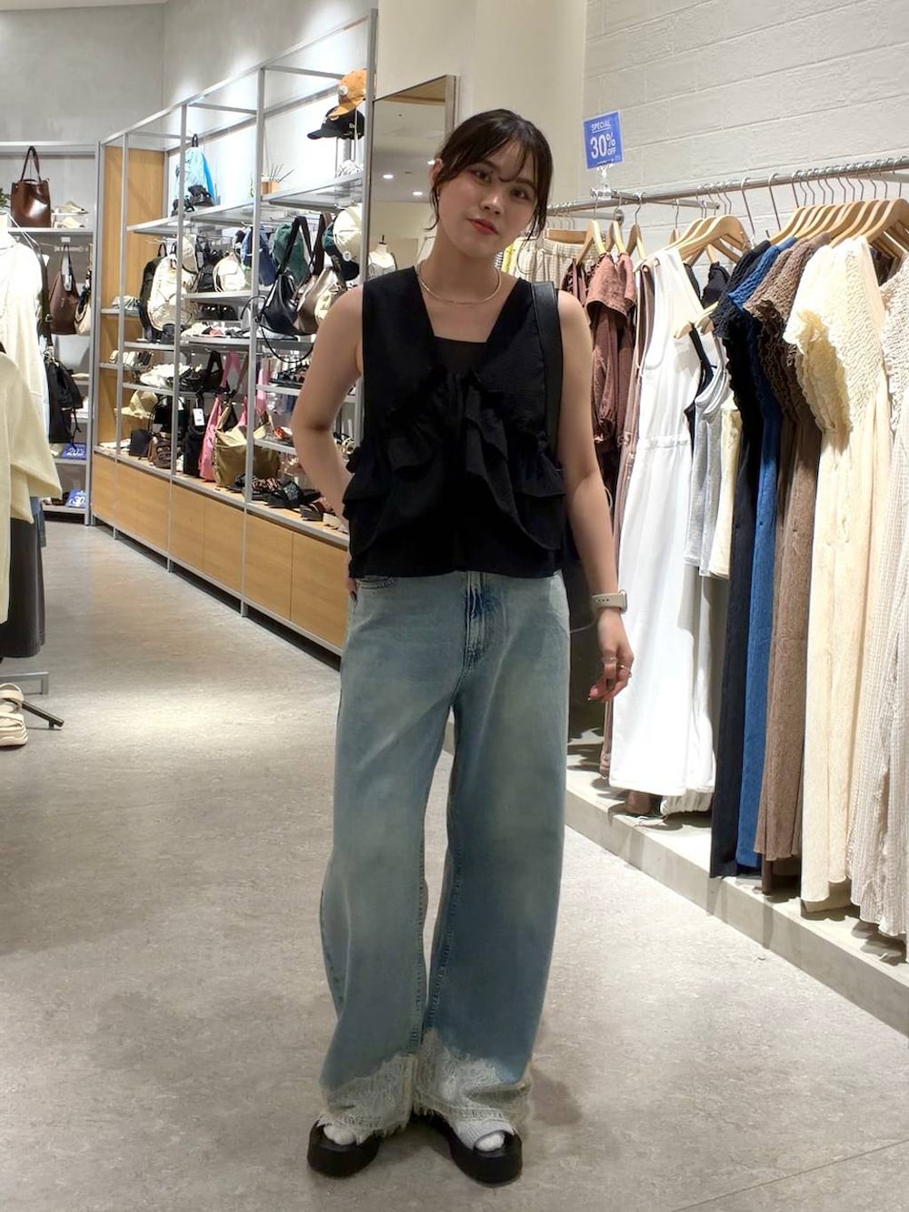 ブルー系のデニムパンツ、ブラック系のトートバッグ、シルバー系のサンダルを着用したレディースの夏コーディネートの4枚目の写真