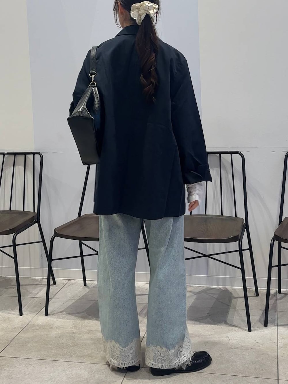 ブルー系のデニムパンツ、ブラック系のショルダーバッグ、ブラック系のローファーを着用したレディースの春コーディネートの7枚目の写真