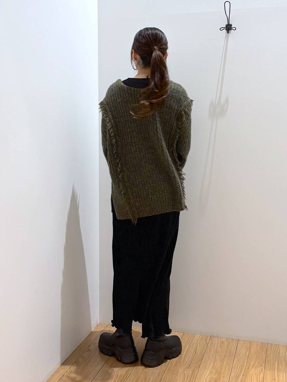 グリーン系のニット/セーター、ブラック系のTシャツ/カットソー、ブラック系のブーツを着用したレディースの冬コーディネートの4枚目の写真