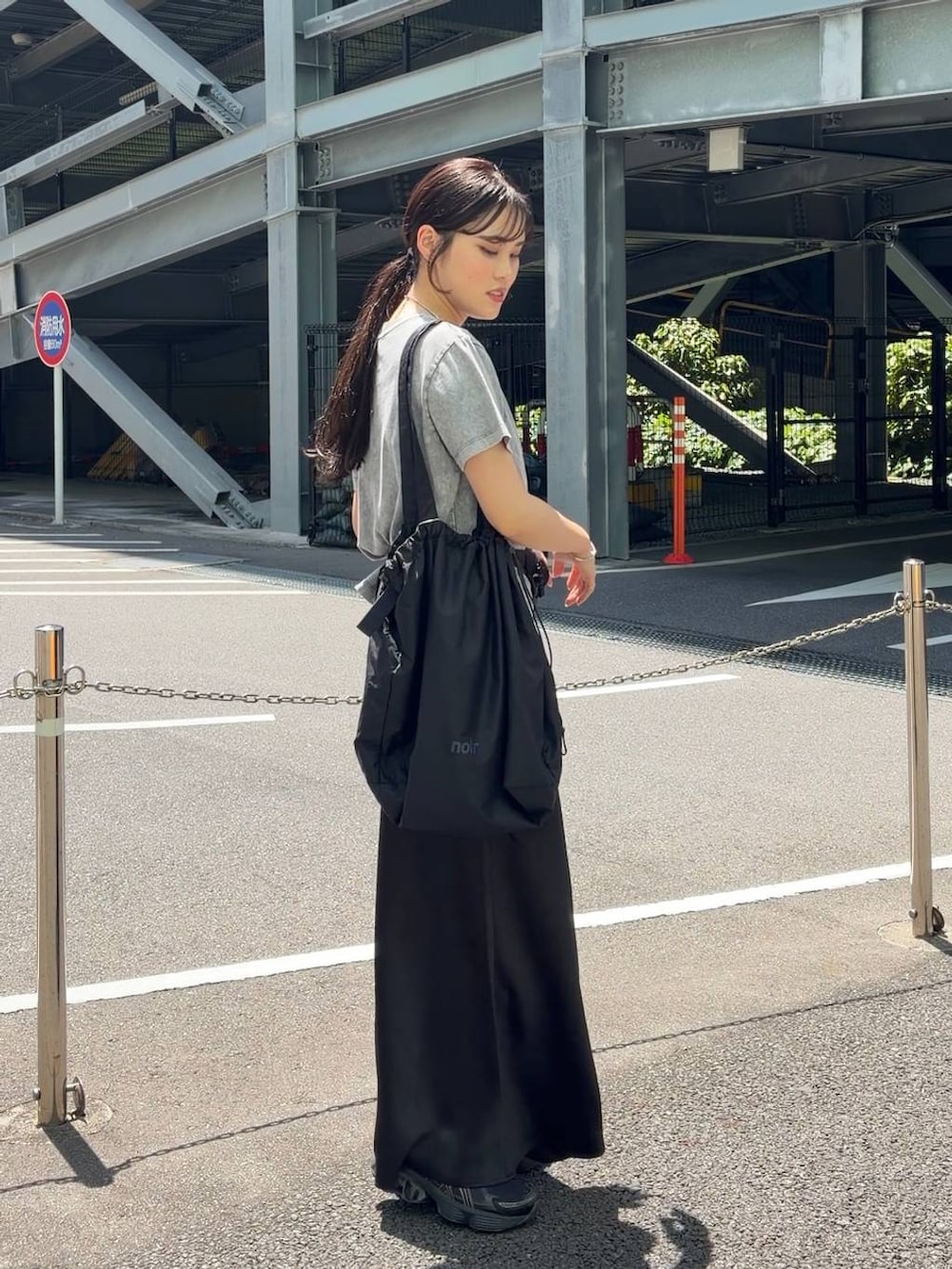 ブラック系のスカート、ブラック系のショルダーバッグ、グレー系のTシャツ/カットソーを着用したレディースの春コーディネートの2枚目の写真