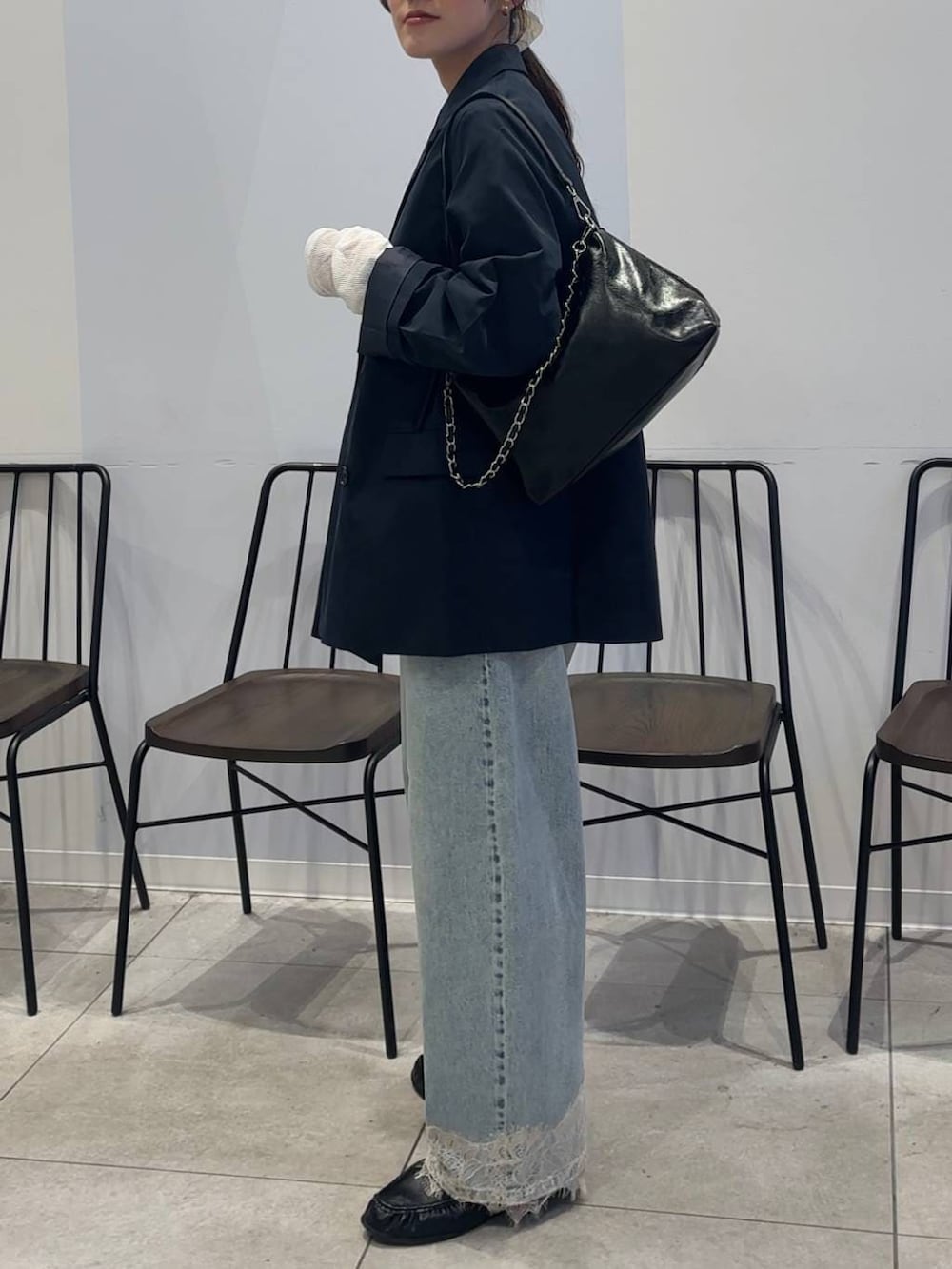 ブルー系のデニムパンツ、ブラック系のショルダーバッグ、ブラック系のローファーを着用したレディースの春コーディネートの6枚目の写真