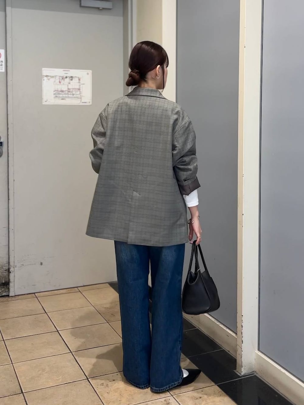 グレー系のテーラードジャケット、ブラック系のショルダーバッグ、ブルー系のデニムパンツを着用したレディースの秋コーディネートの4枚目の写真