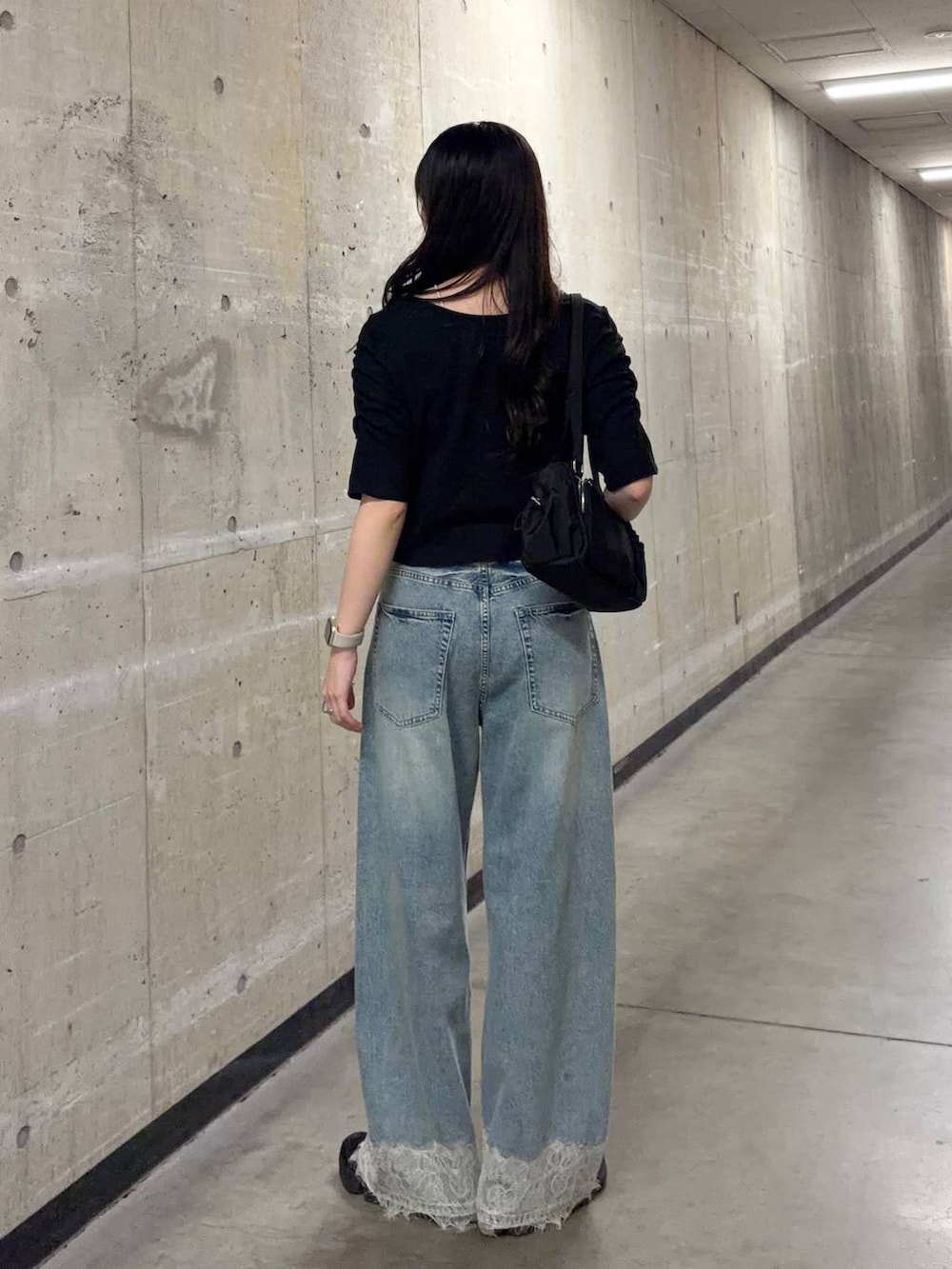 ブルー系のデニムパンツ、ブラック系のTシャツ/カットソー、ブラック系のボストンバッグを着用したレディースの夏コーディネートの3枚目の写真