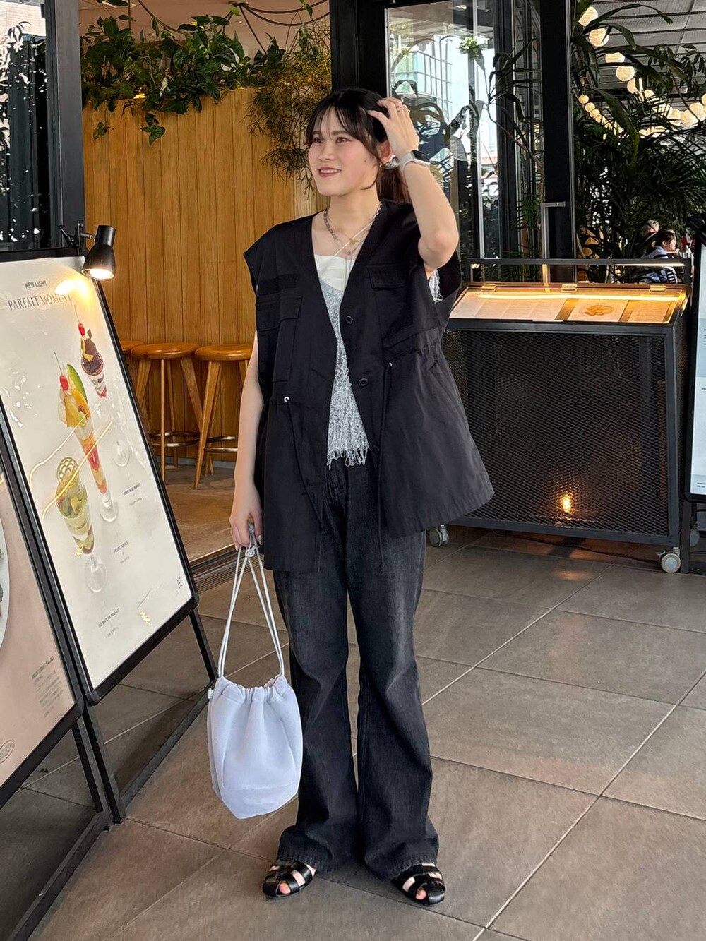 グレー系のショルダーバッグ、ブラック系のサンダル、ホワイト系のベストを着用したレディースの夏コーディネートの4枚目の写真