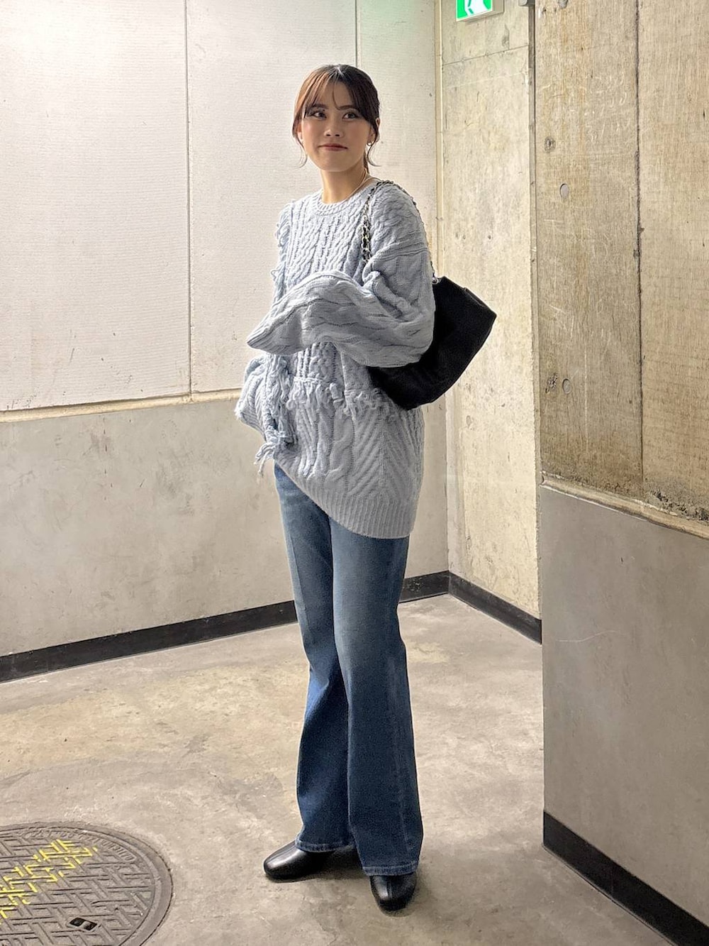 ブルー系のニット/セーター、ブルー系のデニムパンツ、ブラック系のショルダーバッグを着用したレディースの秋コーディネートの7枚目の写真