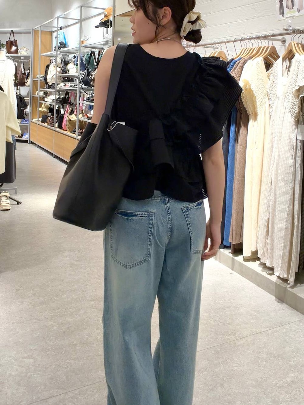 ブルー系のデニムパンツ、ブラック系のトートバッグ、シルバー系のサンダルを着用したレディースの夏コーディネートの5枚目の写真