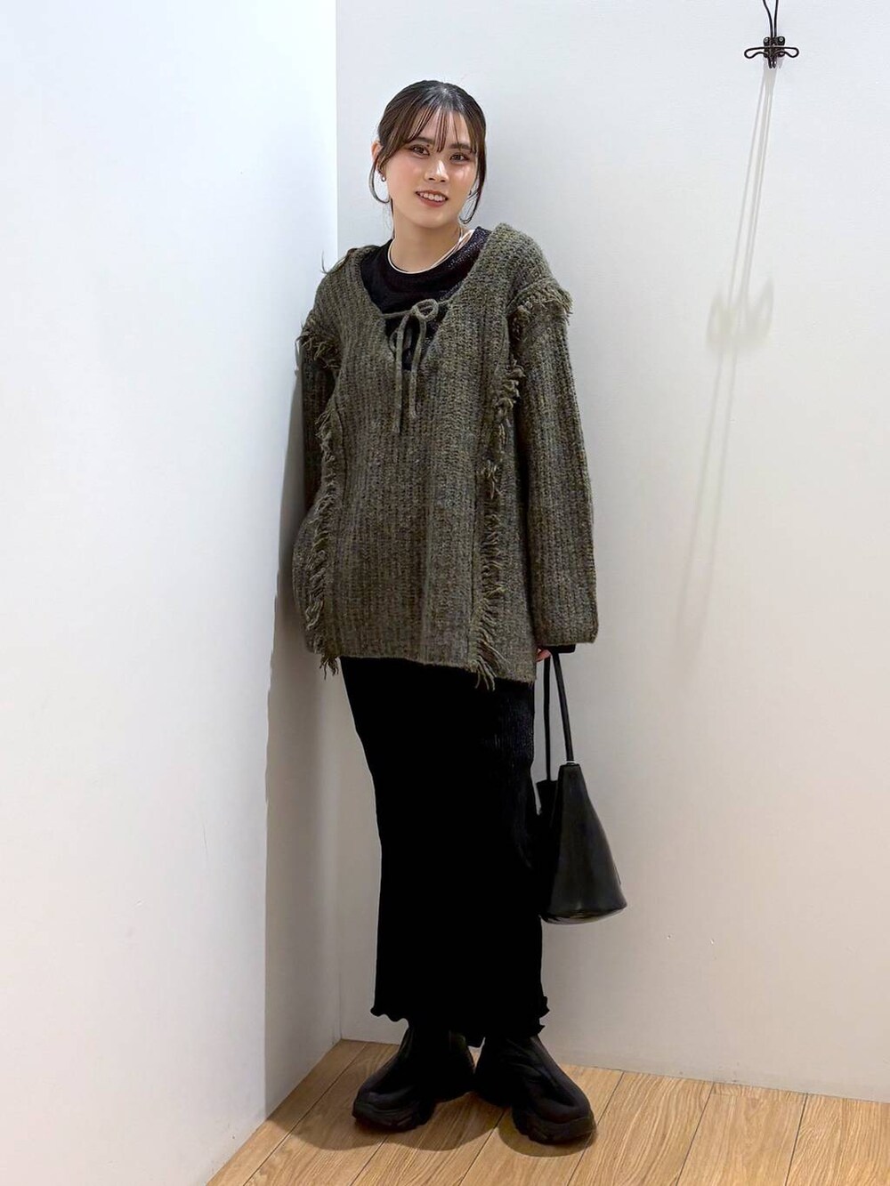 グリーン系のニット/セーター、ブラック系のTシャツ/カットソー、ブラック系のブーツを着用したレディースの冬コーディネートの5枚目の写真
