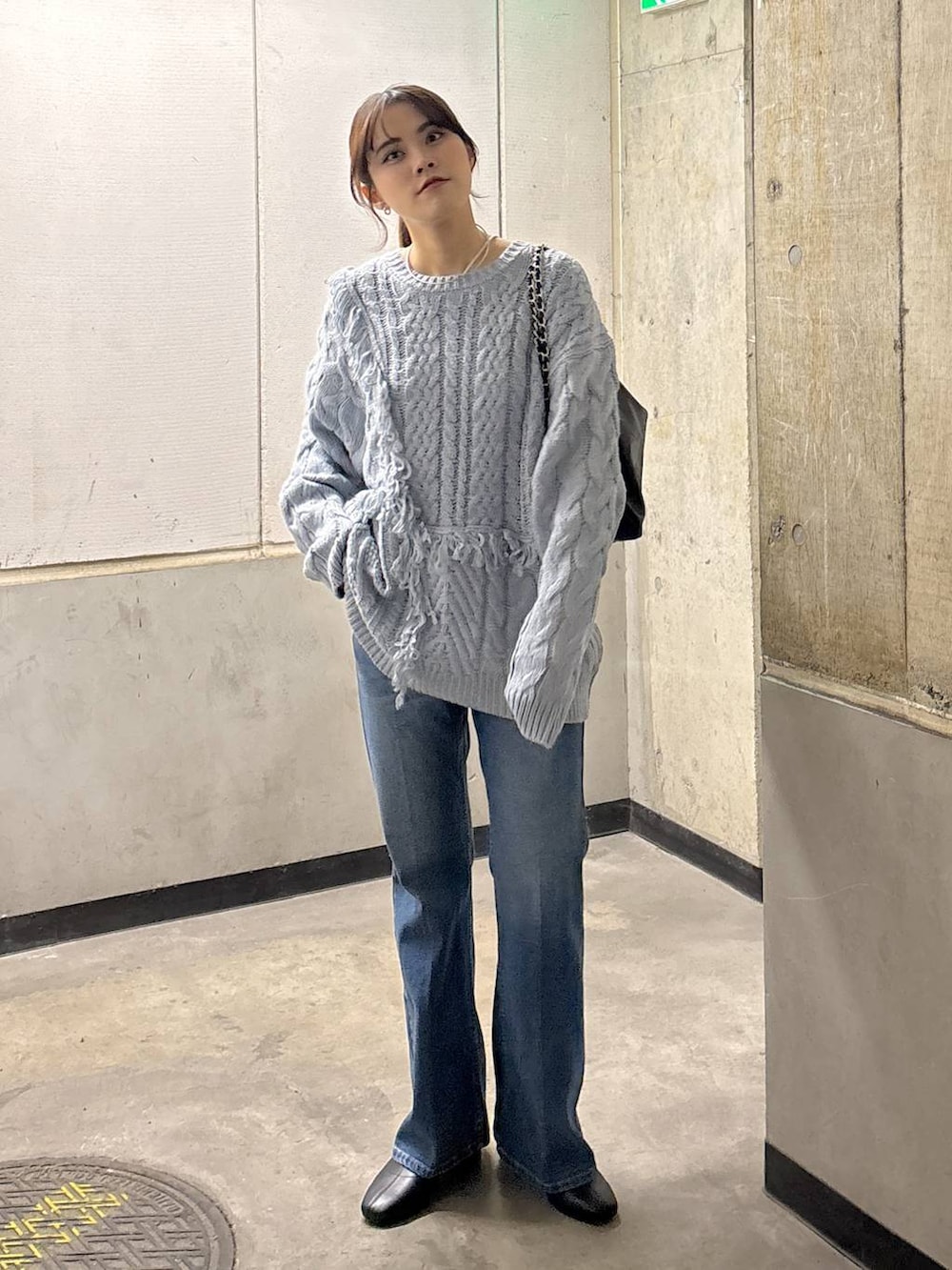 ブルー系のニット/セーター、ブルー系のデニムパンツ、ブラック系のショルダーバッグを着用したレディースの秋コーディネートの3枚目の写真