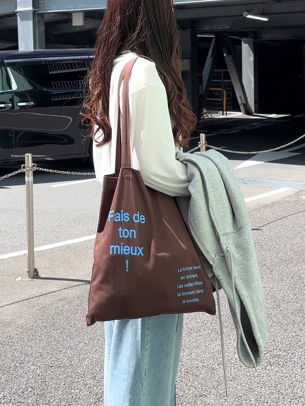 ホワイト系のTシャツ/カットソー、ブラウン系のトートバッグ、ブルー系のデニムパンツを着用したレディースの春コーディネートの3枚目の写真