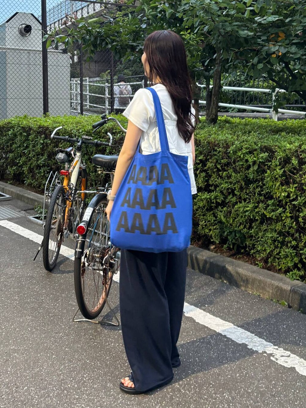 ホワイト系のTシャツ/カットソー、ブラック系のサンダル、ホワイト系のキャミソールを着用したレディースの夏コーディネートの4枚目の写真