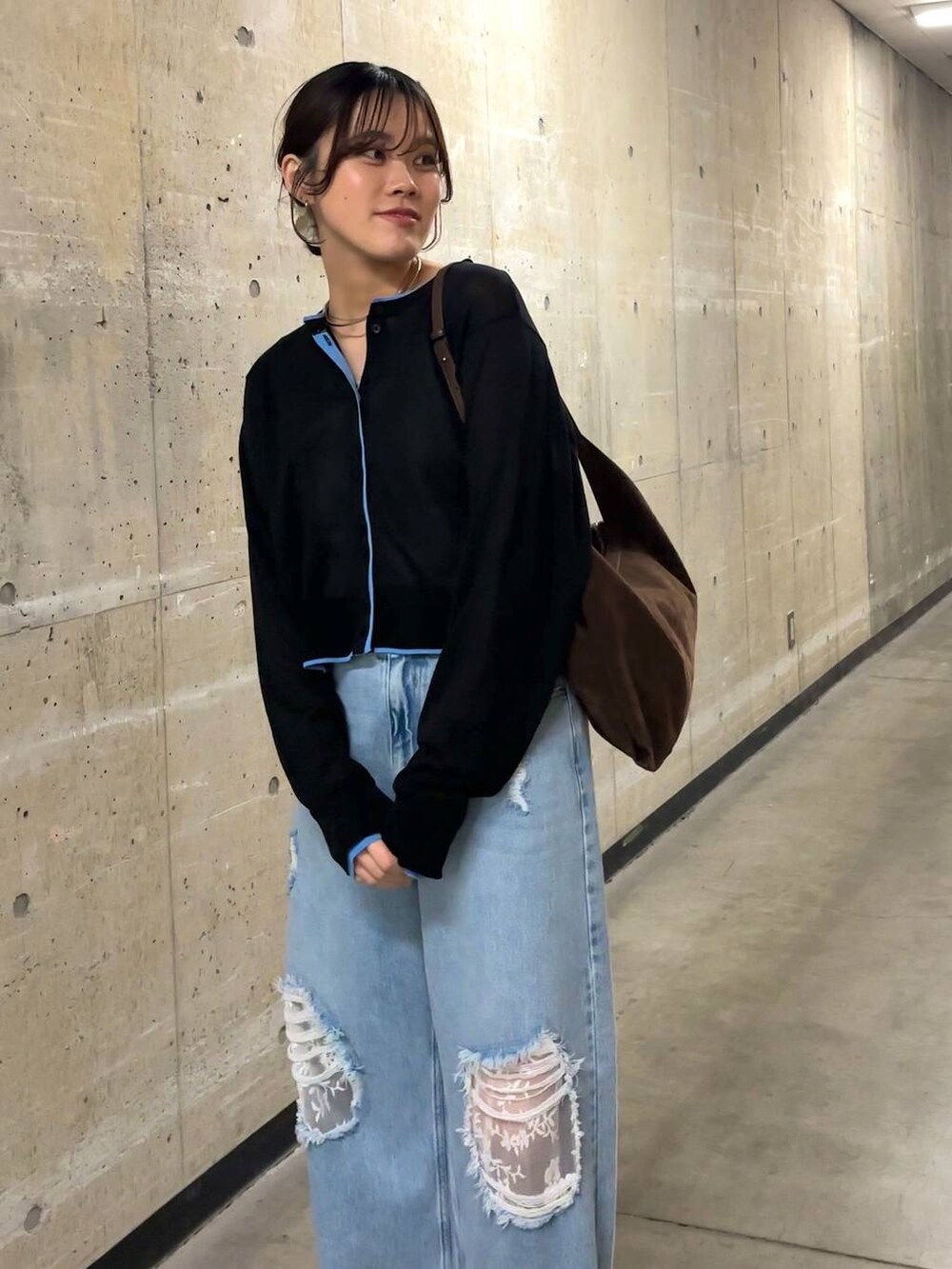 ブルー系のデニムパンツ、ブラウン系のショルダーバッグ、ブラック系のカーディガン/ボレロを着用したレディースの春コーディネートの5枚目の写真