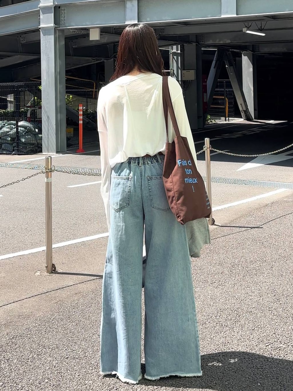 ホワイト系のTシャツ/カットソー、ブラウン系のトートバッグ、ブルー系のデニムパンツを着用したレディースの春コーディネートの9枚目の写真