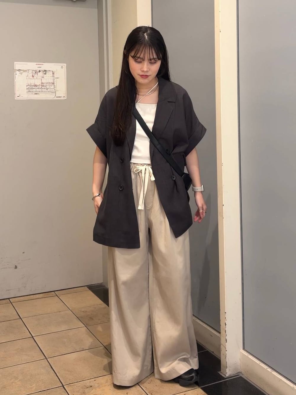 ベージュ系のデニムパンツ、グレー系のテーラードジャケット、ブラック系のショルダーバッグを着用したレディースの夏コーディネートの6枚目の写真