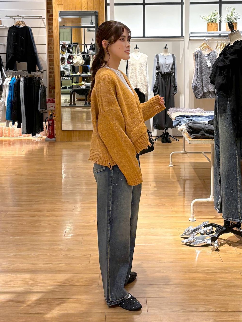 ブルー系のデニムパンツ、ブラック系のバレエシューズ、ブラック系のボストンバッグを着用したレディースの秋コーディネートの3枚目の写真