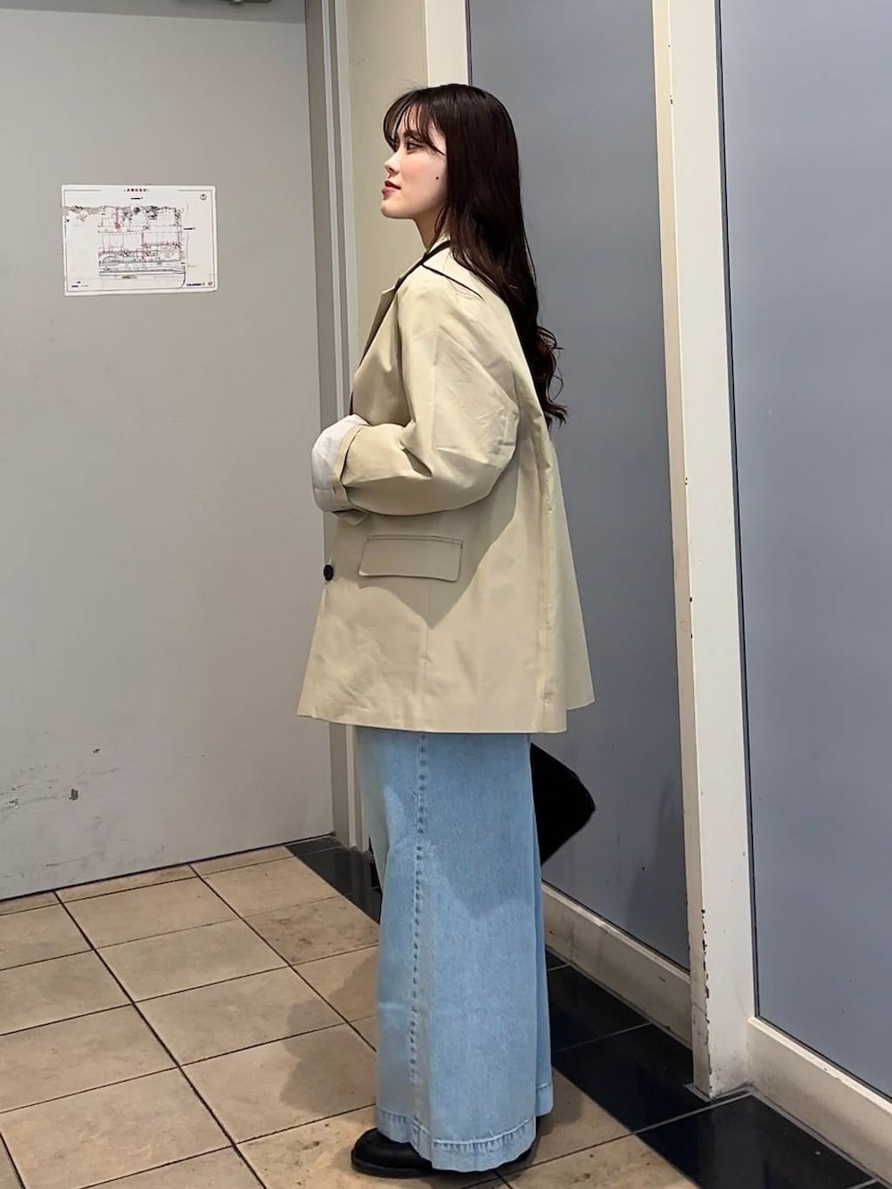 ブラック系のローファー、ブルー系のデニムパンツ、ブラック系のショルダーバッグを着用したレディースの冬コーディネートの2枚目の写真