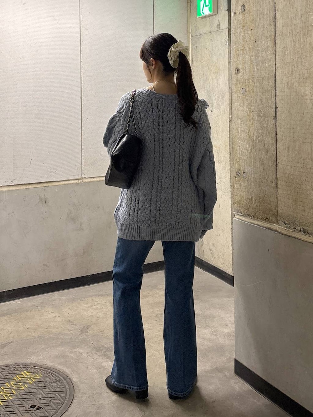 ブルー系のニット/セーター、ブルー系のデニムパンツ、ブラック系のショルダーバッグを着用したレディースの秋コーディネートの5枚目の写真