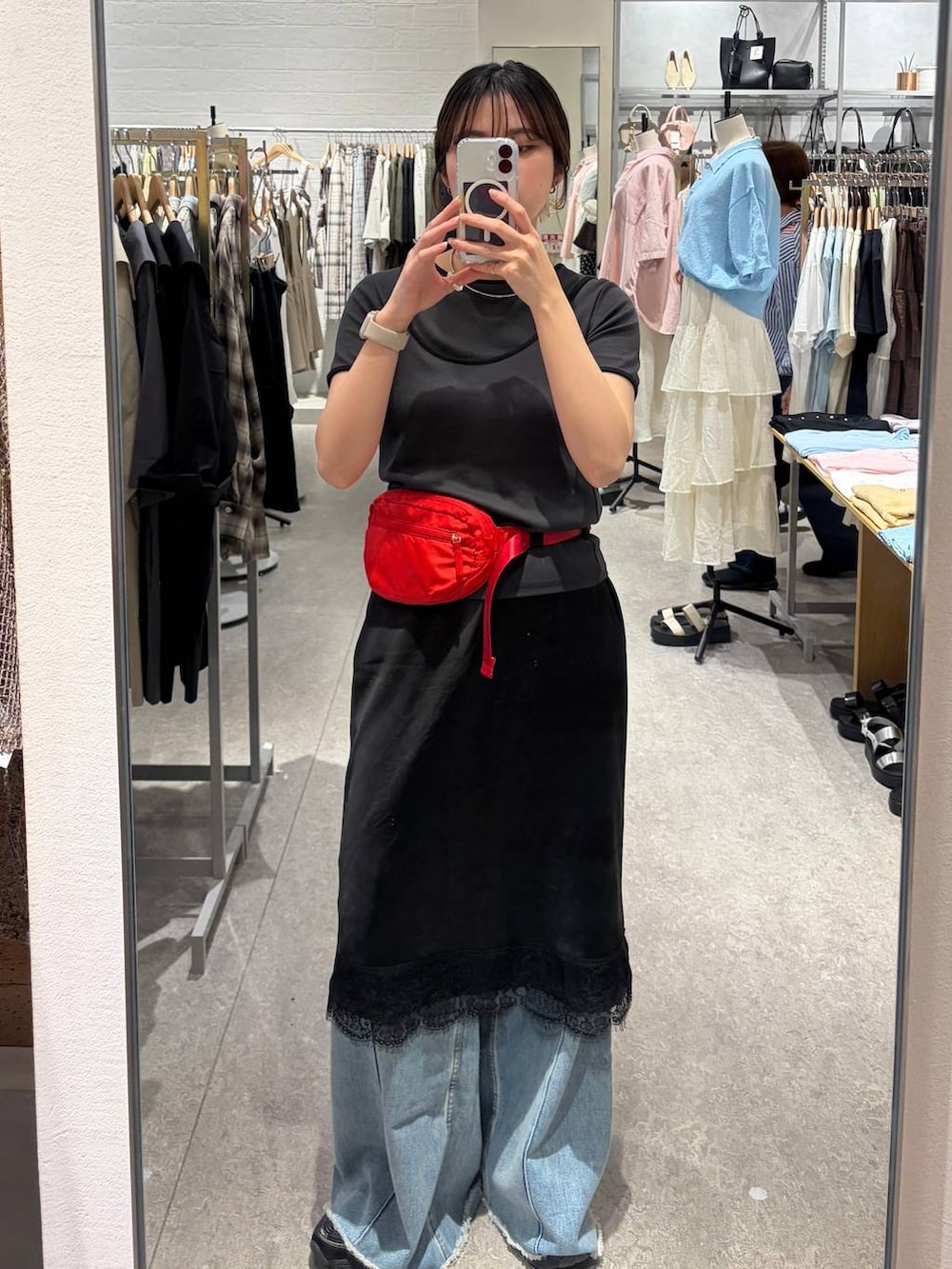 ブルー系のデニムパンツ、レッド系のボディバッグ/ウエストポーチ、ブラック系のスカートを着用したレディースの春コーディネートの2枚目の写真