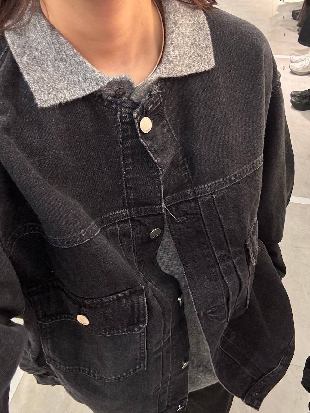 ブラック系のデニムジャケット、グレー系のニット/セーターを着用したレディースの秋コーディネートの3枚目の写真