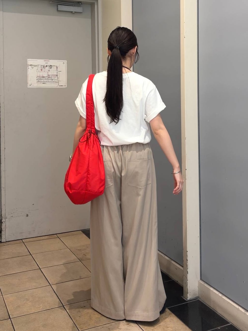 ベージュ系のデニムパンツ、レッド系のショルダーバッグ、ホワイト系のTシャツ/カットソーを着用したレディースの春コーディネートの4枚目の写真
