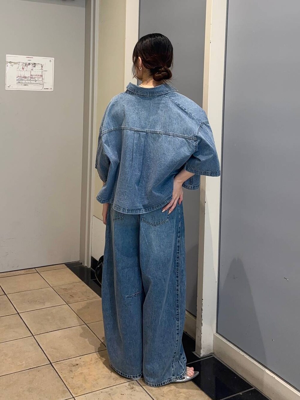 シルバー系のサンダル、ブルー系のデニムパンツ、ブラック系のショルダーバッグを着用したレディースの夏コーディネートの3枚目の写真