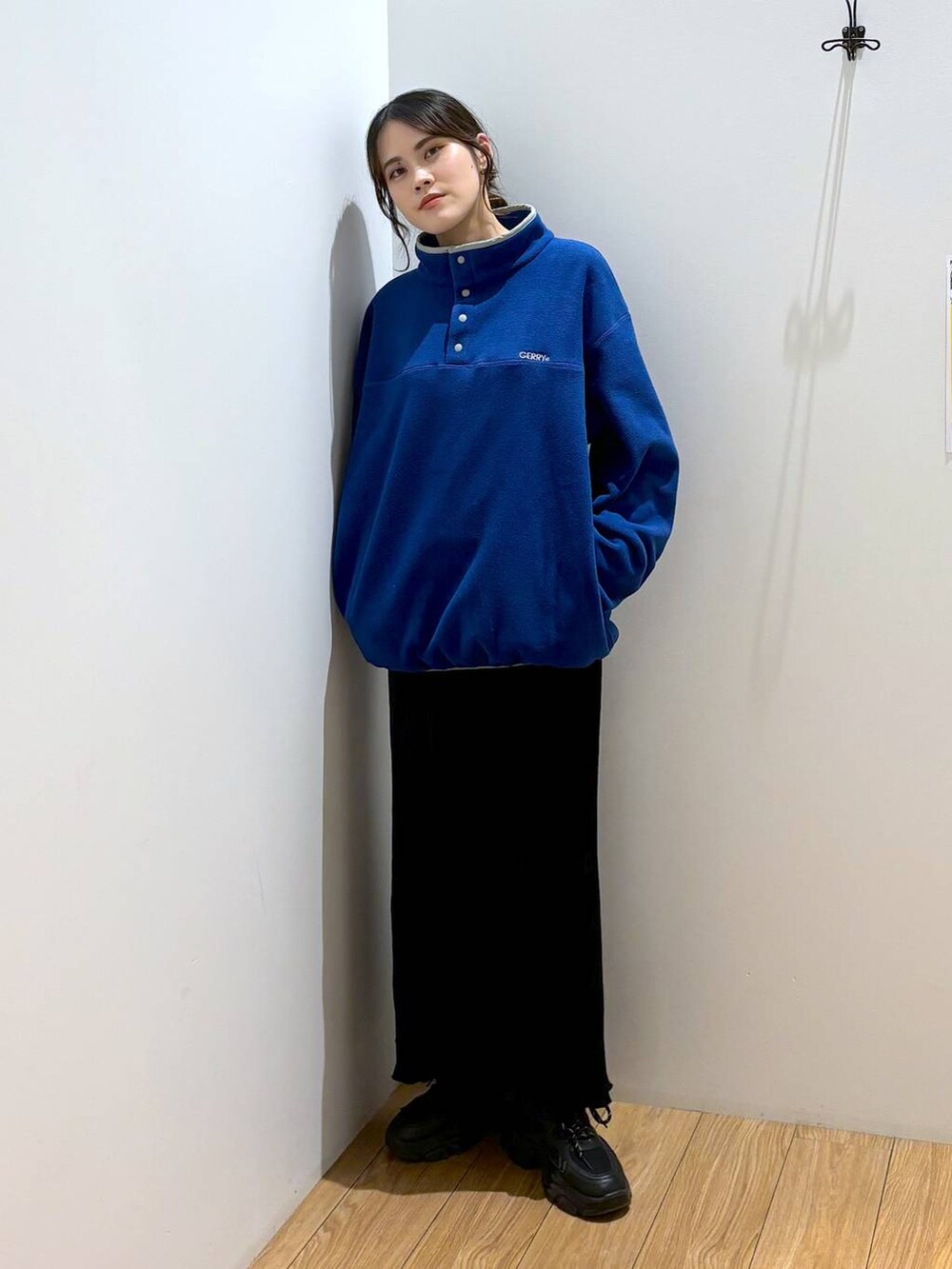 ブラック系のスカート、ブルー系のTシャツ/カットソー、ブラック系のスニーカーを着用したレディースの秋コーディネートの5枚目の写真