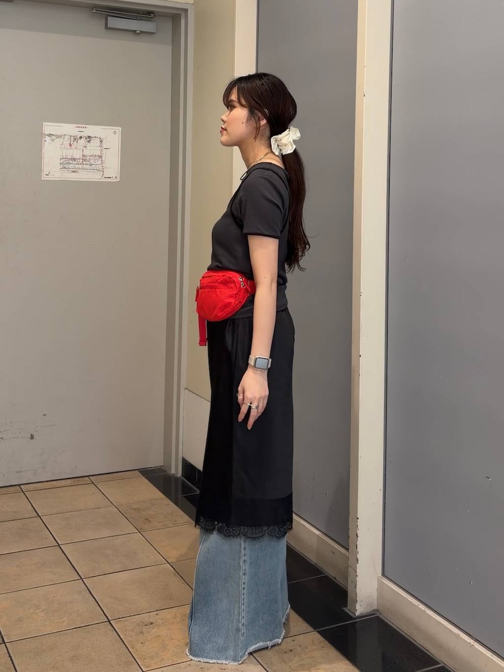 ブルー系のデニムパンツ、レッド系のボディバッグ/ウエストポーチ、ブラック系のスカートを着用したレディースの春コーディネートの2枚目の写真
